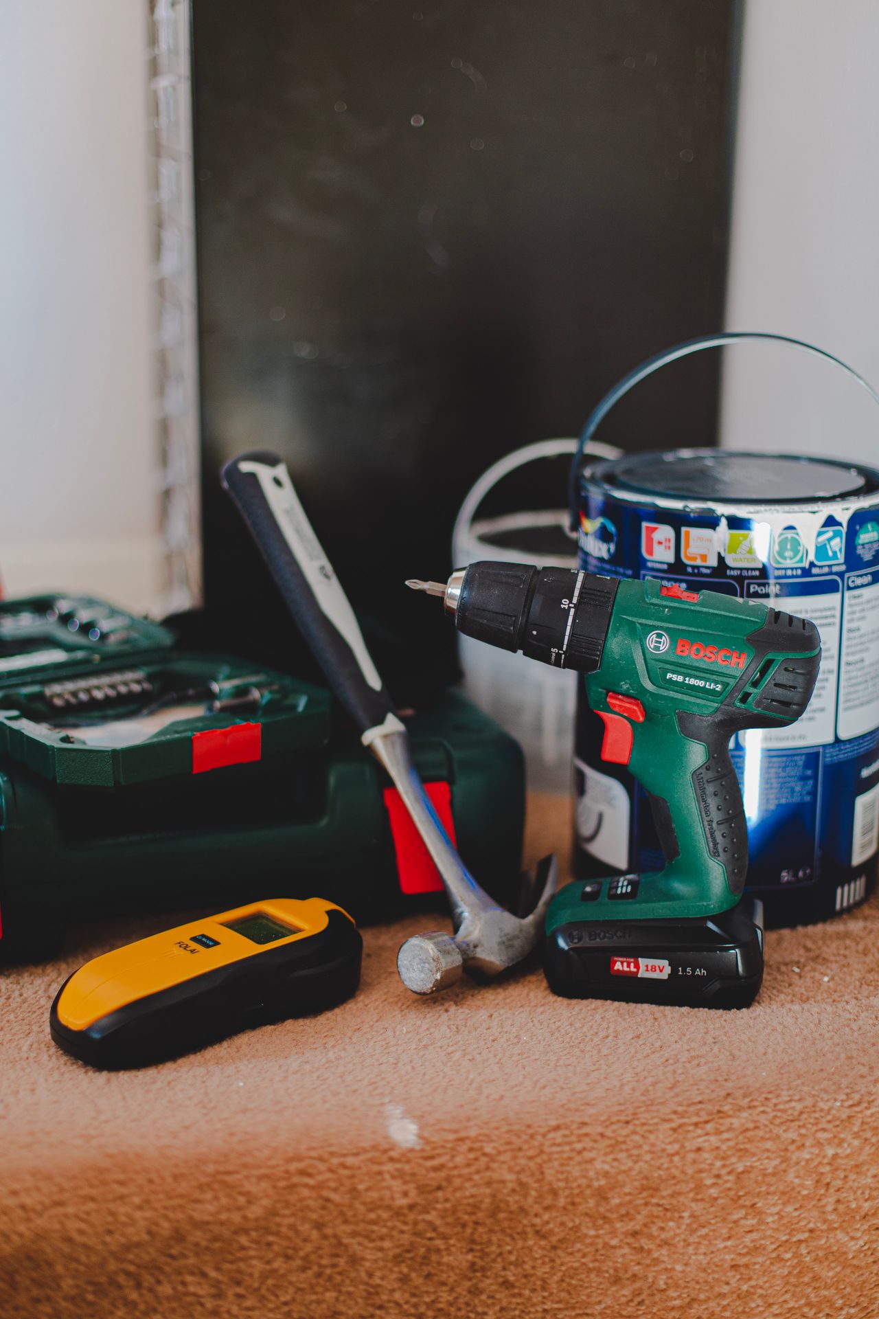 Tools with a cordless screwdriver, wire detector and spirit level on a wooden floor